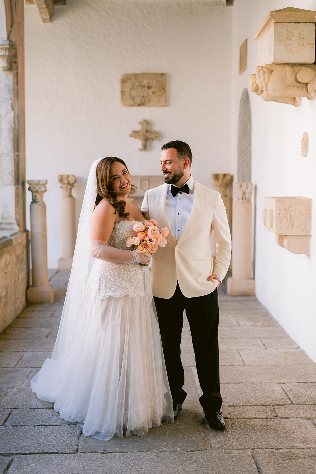 Mana and Jordi smiling together in a stone corridor at Castell Peralada on their wedding day
